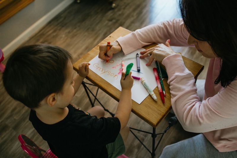 Una cuidadora y un niño dibujando juntos
